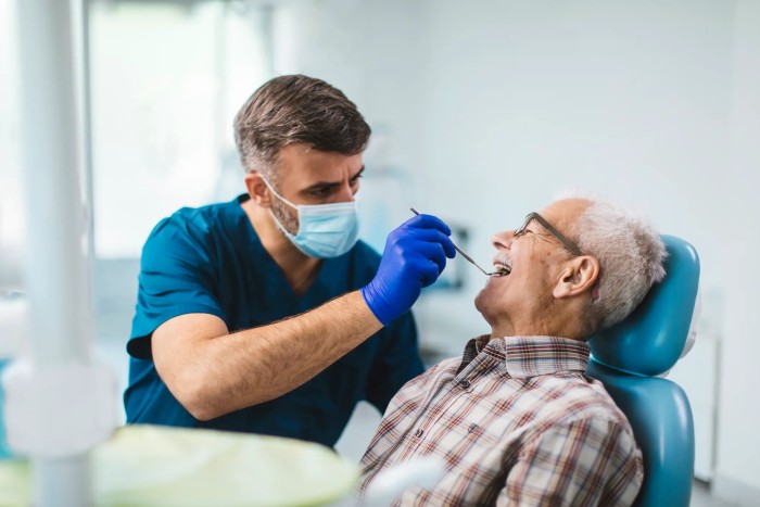 Older adult visiting a dental office for tooth decay prevention or treatment while the dentist examines and treats them