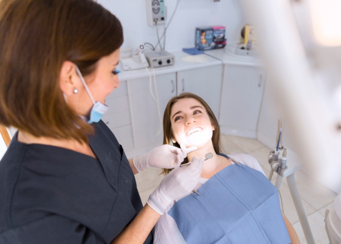 Woman visiting the dentist for a regular dental check-up while the dentist prepares to examine her