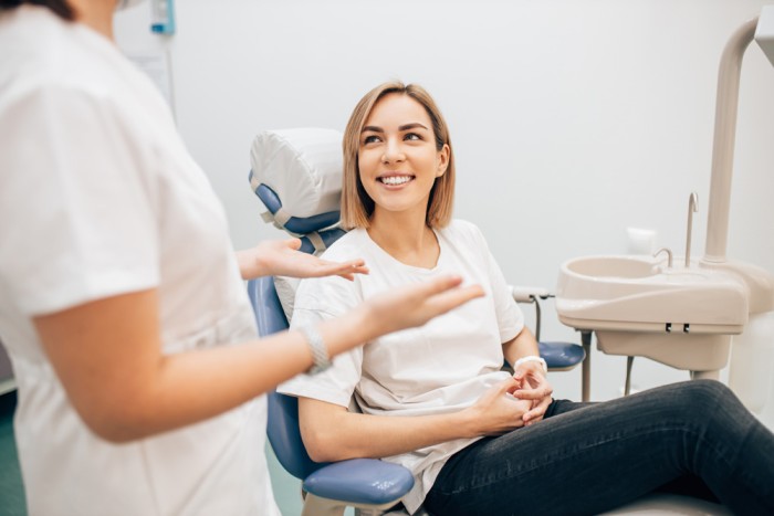 A young woman is sitting in the dental chair while the dentist is explaining the dietary restrictions after teeth whitening.