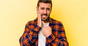 a man is suffering from a toothache caused by common dental problems