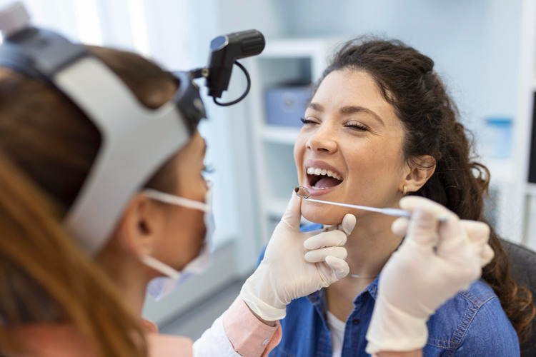 a woman in dental checkup session being examined by a dentist