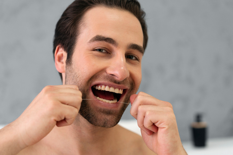 A man is flossing his teeth properly