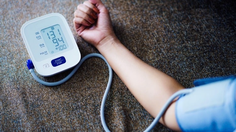 Digital blood pressure monitor next to a man’s hand