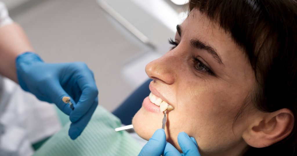 A young woman sitting calmly in a dental chair while a dentist places a dental crown.