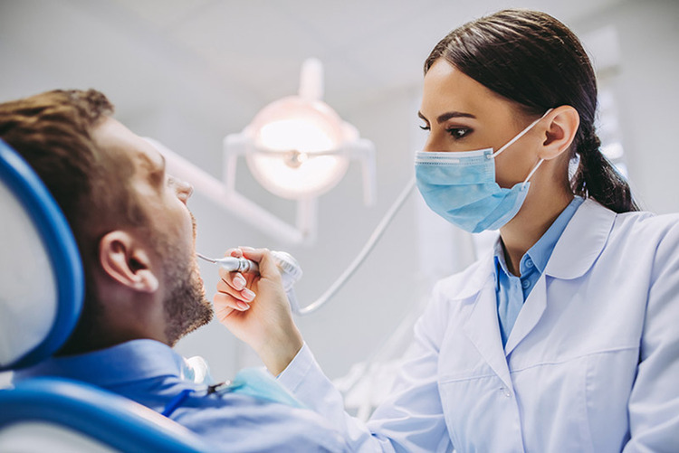 Female dentist providing emergency dental treatment to a patient with complications from rotten teeth