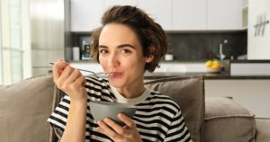 Young woman happily eating soft food after wisdom tooth extraction during recovery