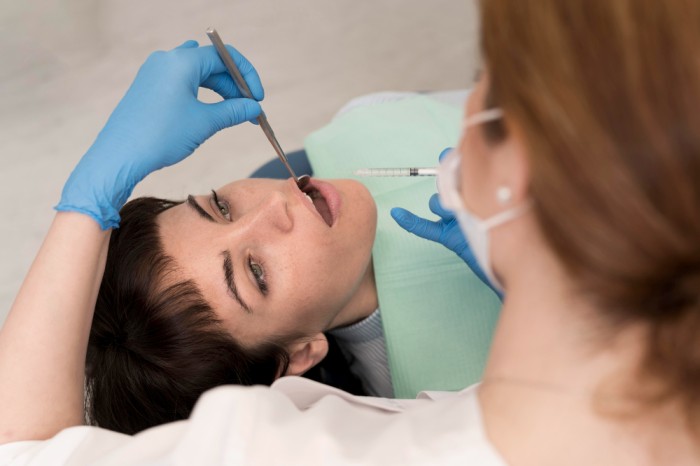 Female dentist administering dental numbing to a female patient
