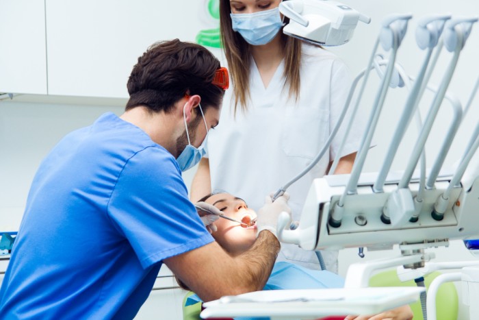Dentist and dental assistant performing a dental procedure on a patient after dental numbing, in a dental office