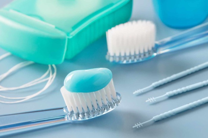 A toothbrush with toothpaste alongside dental floss and home oral care products